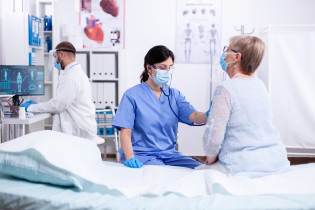 Cardiologist,Assistant,Listening,Heart,Of,Senior,Woman,With,Stethoscope,During